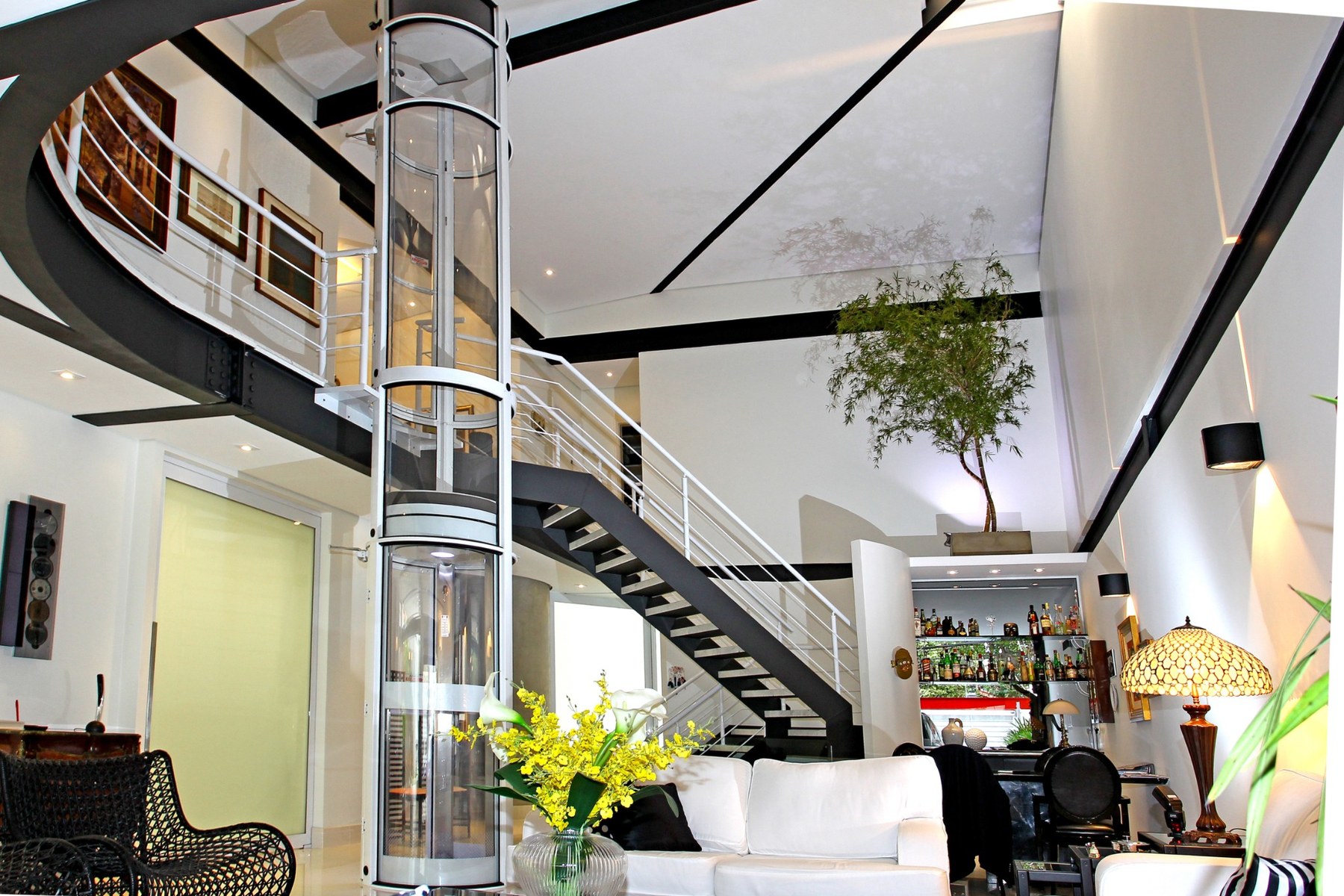 Elevador residencial atravessando diferentes pavimentos e convivendo com a escada existente