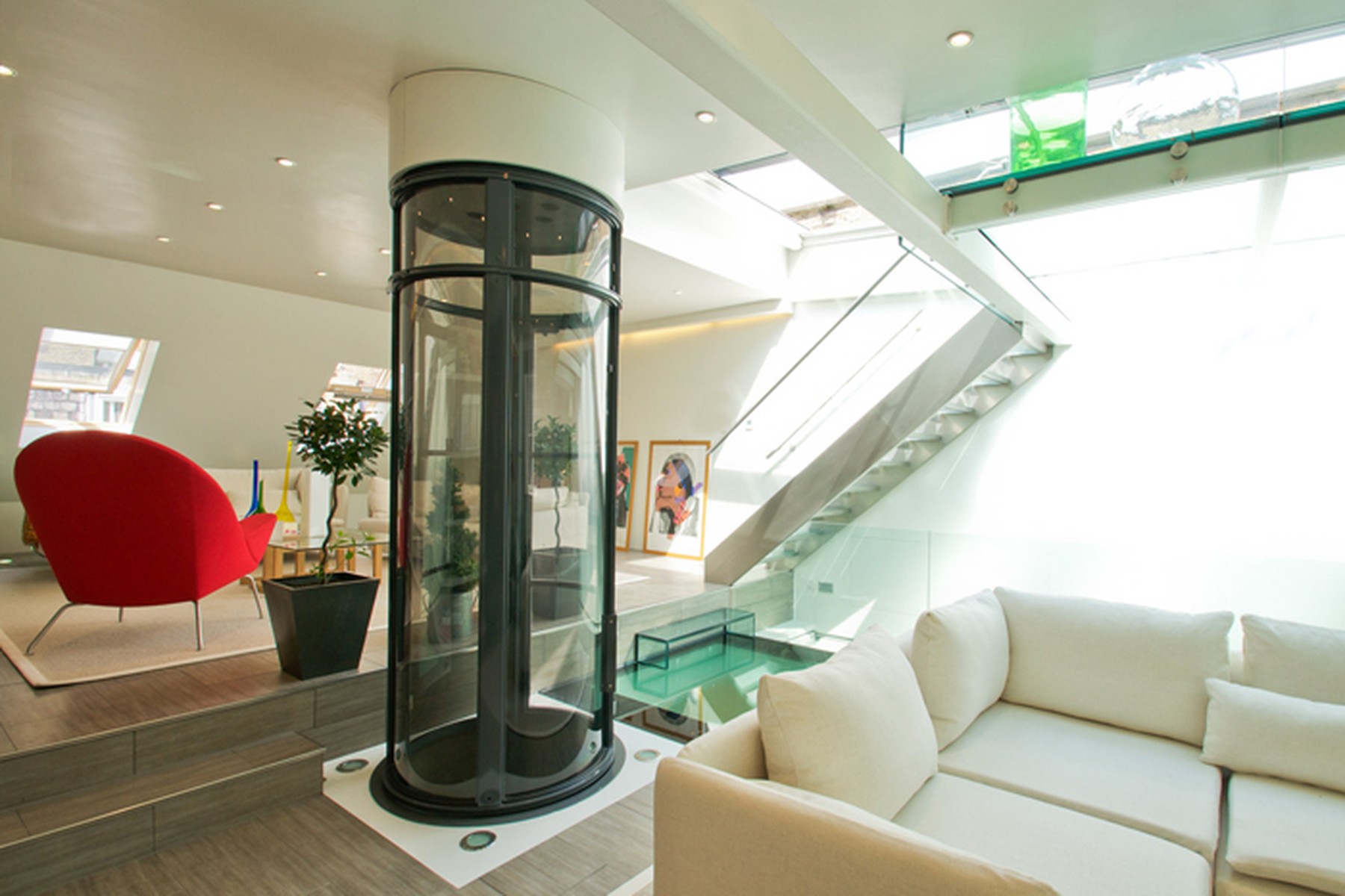 Elevador residencial panorâmico integrado a uma sala contemporânea com pé-direito aberto